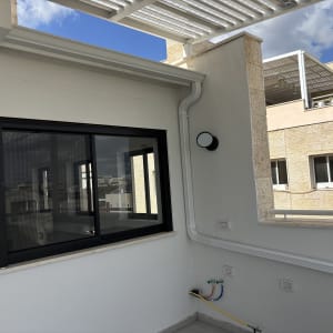 גג עם פרגולה מתכתית וחלון זכוכית גדול