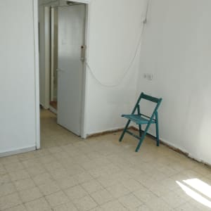 חדר עם קירות לבנים וכיסא מתקפל ירוק