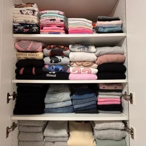 בגדים מקופלים ומסודרים בארון לבן עם מדפים