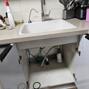 כיור מטבח עם ארון פתוח וצנרת גלויה מתחת