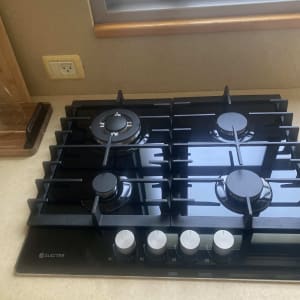 כיריים גז שחורות עם ארבעה מבערים וכפתורי שליטה