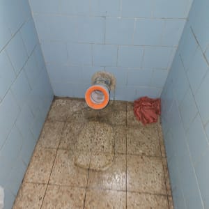 צינור ביוב עם אריחים רטובים וקיר אריחים כחול