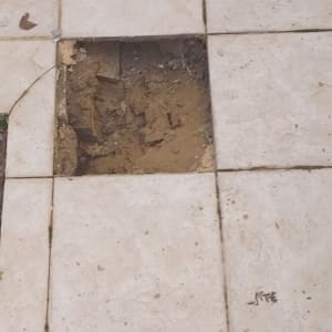 מרצפת חסרה ברצפת קרמיקה עם אדמה חשופה