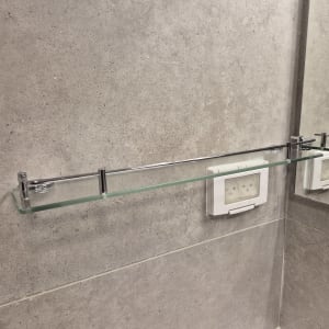 מדף זכוכית מותקן על קיר בחדר אמבטיה
