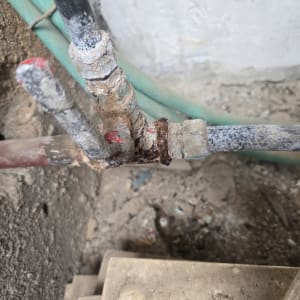 חיבור צנרת מים חלוד ובלוי בתוך קיר לפני תיקון נזקי צנרת