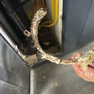 צינור חלוד ומקולף מוחזק ביד ליד צינורות צהובים