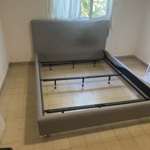 מיטה מפורקת בחדר ריק עם חלון פתוח