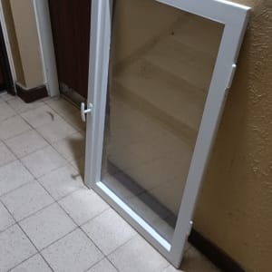 חלון זכוכית עם מסגרת לבנה מונח על הרצפה