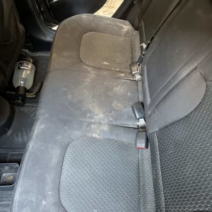 מושב רכב מלוכלך עם כתמים ובקבוק חומר ניקוי