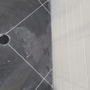 ריצוף חדש במקלחת עם אריחים כהים וניקוז