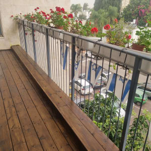 מרפסת עץ עם עציצים ופרחים אדומים על המעקה