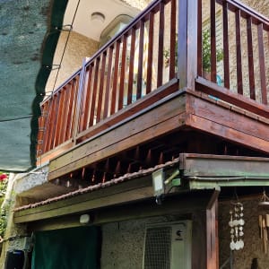 מרפסת עץ עם מעקה, פעמוני רוח תלויים