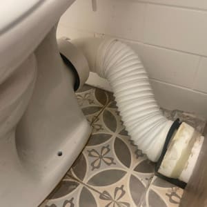 אסלה וצינור חיבור לבן על רצפה מעוצבת