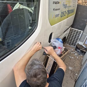 אדם פותח דלת רכב עם כלי עבודה