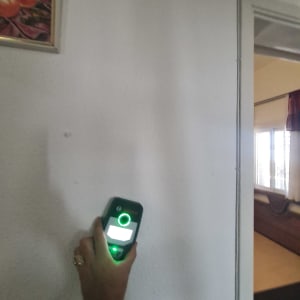 יד מחזיקה מכשיר מדידה על קיר לבן