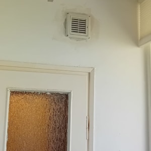 פתח אוורור על קיר לבן ליד דלת