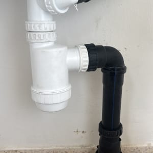 צנרת פלסטיק לבנה ושחורה מתחת לכיור