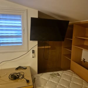 טלוויזיה מותקנת על קיר בחדר שינה עם מדפים