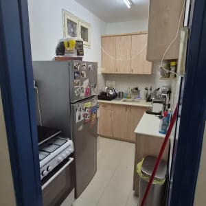מבט לתוך מטבח ביתי בדירה כולל מקרר, תנור וארונות מטבח