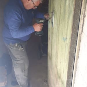 אדם מתקין מנעול בדלת עם מברגה חשמלית