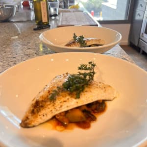 צלחת עם דג מעוטר בעשבי תיבול על שולחן מטבח