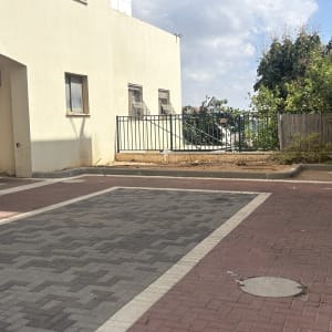 חצר עם שביל מרוצף ועצים ברקע