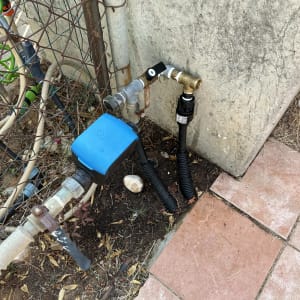 צינור מים עם ברז וכיסוי כחול ליד קיר