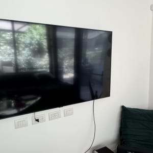 טלוויזיה תלויה על קיר עם שקעים וכבלים