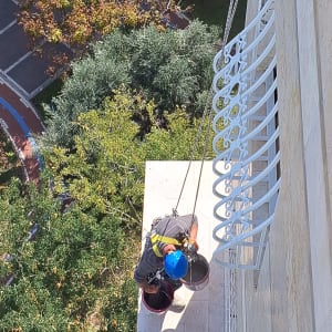 אדם עם קסדה כחולה עובד בגובה עם חבלים ודליים