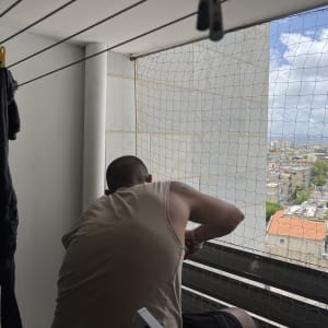 אדם מתקין רשת למניעת כניסת יונים במרפסת