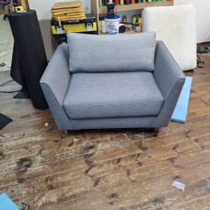 ספה אפורה בסטודיו לריפוד עם כלים וחומרים מסביב