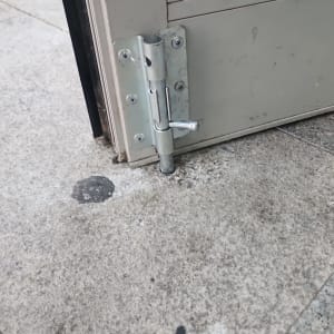 בריח מתכת על דלת זכוכית עם רצפה אפורה