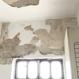 קיר מתקלף עם חלון וכלי עבודה לצביעה