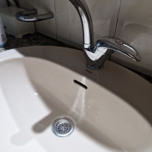 ברז נירוסטה מטפטף מעל כיור לבן