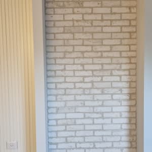 קיר לבנים חשופות עם סימני שיפוץ על הרצפה