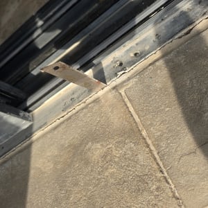 סדק ברצפה ליד מסגרת חלון עם כלי מדידה