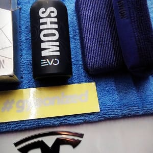 בקבוק שחור, מגבת כחולה, מדבקה צהובה, לוגו רכב