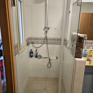 מקלחת עם ראש מקלחת, בקבוקי סבון ומגבת