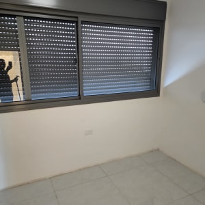 צללית אדם עם מטאטא ליד חלון עם תריסים סגורים