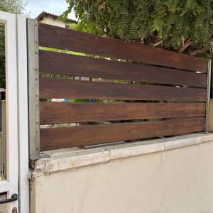 גדר עץ חומה על קיר אבן ליד עץ ירוק
