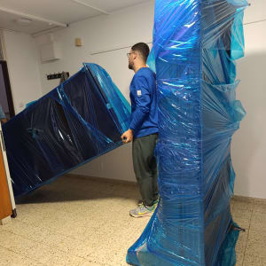 אדם מזיז רהיטים עטופים בניילון כחול