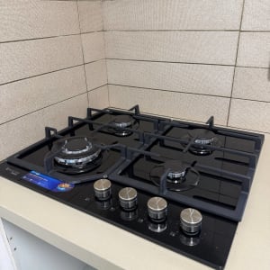 התקנת כיריים גז מודרניים מזכוכית שחורה על משטח עבודה במטבח