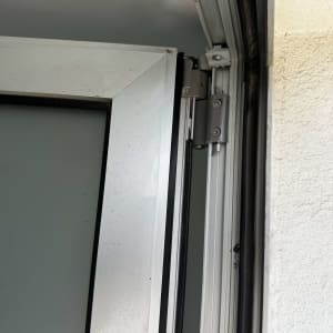 מסגרת חלון עם ציר מתכת וקיר לבן