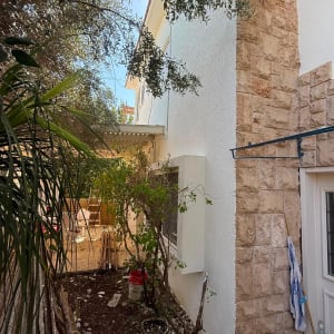 קיר חיצוני של בית פרטי עם חיפוי אבן טבעית וטיח חוץ לבן