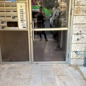 דלת זכוכית בכניסה לבניין מגורים עם מסגרת אלומיניום