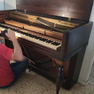 אדם מכוון פסנתר בחדר מואר