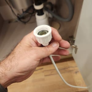 יד מחזיקה חלק של צנרת מתחת לכיור