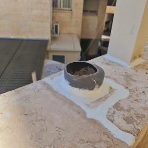 צינור פלסטיק אפור עם חומר איטום על מעקה אבן