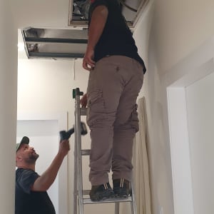 שני אנשים עובדים על התקנת מזגן בתקרה