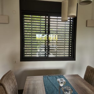 חלון עם תריסי אלומיניום שחורים